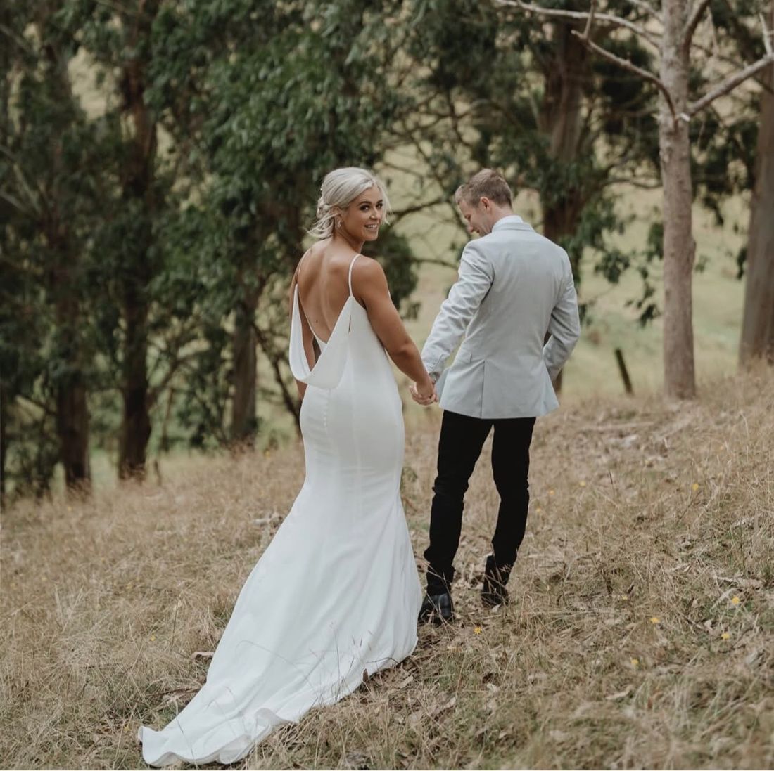 Bride looking back over her shoulder as she walks with her groom