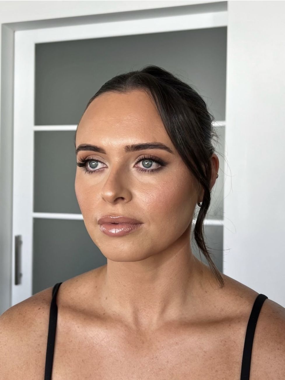 Smoky brown eye with full lashes, bronzed skin and a glossy nude lip
